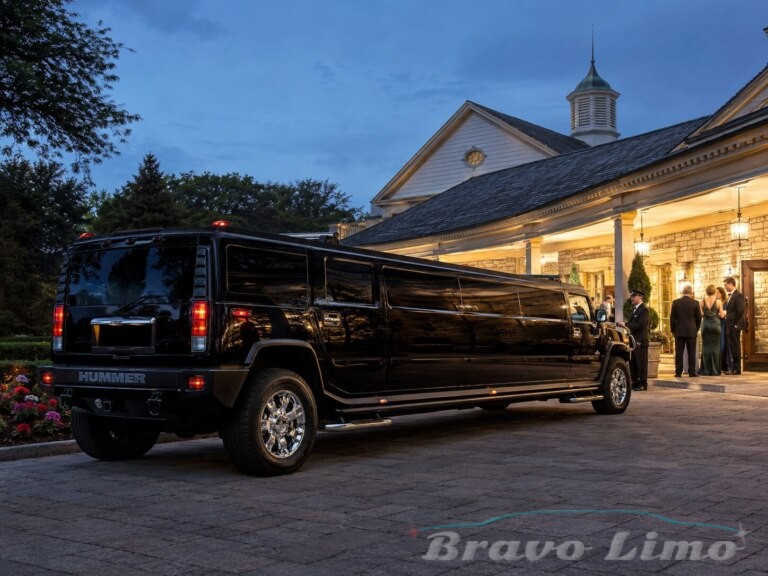 Black Hummer H2 limo parked outside a building at dusk.