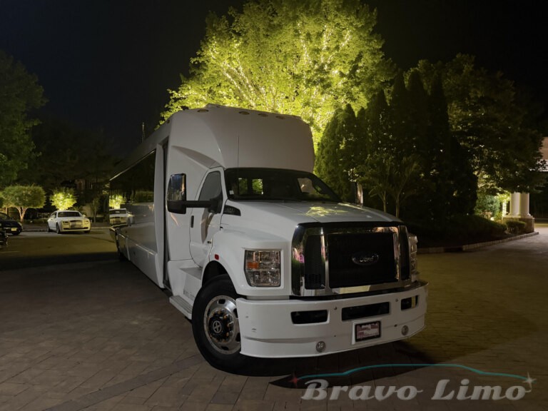White luxury transformer party bus by Bravo Limo at night