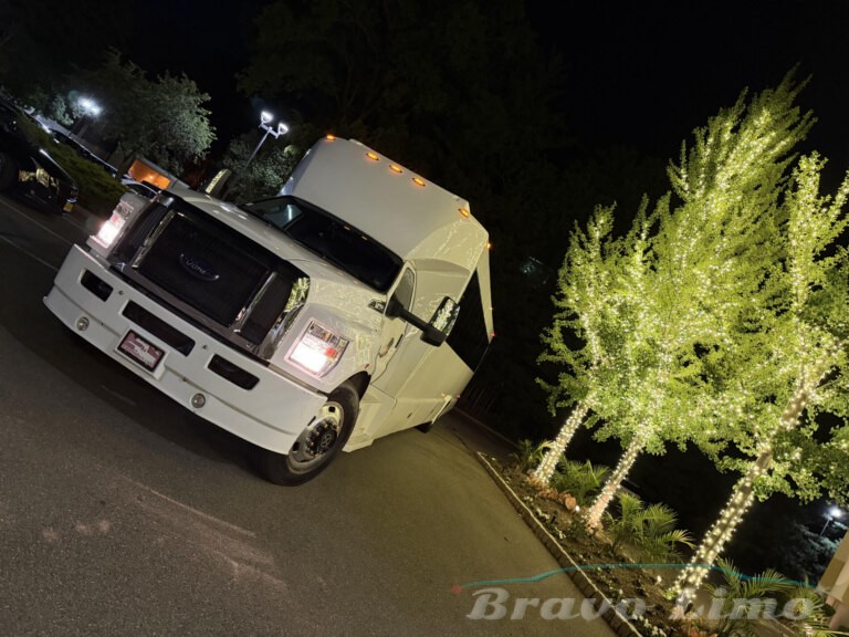 White luxury transformer party bus at night, decorated with lights.