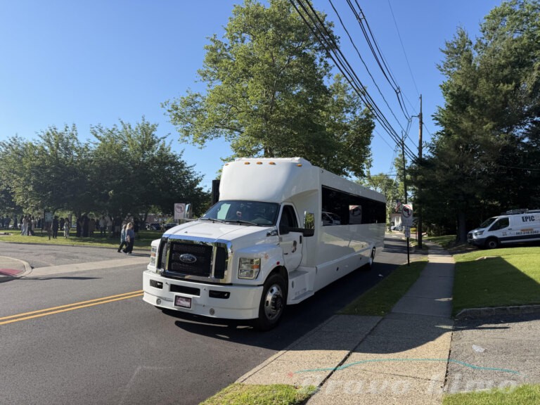 White luxury transformer party bus on a sunny street