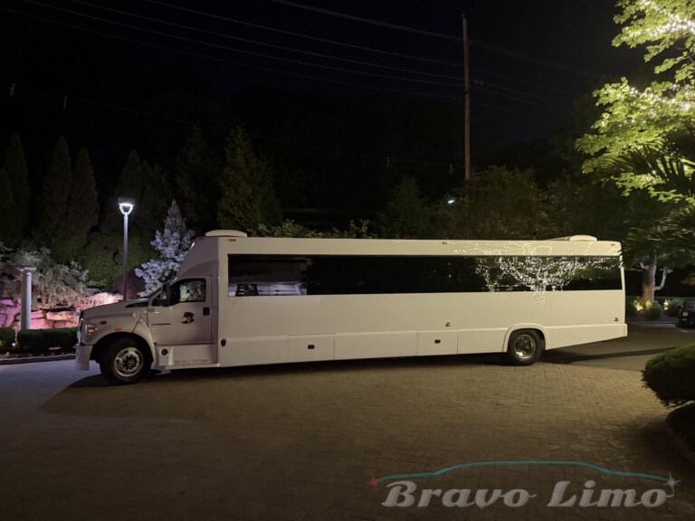 White luxury Transformer party bus parked at night, Bravo Limo.